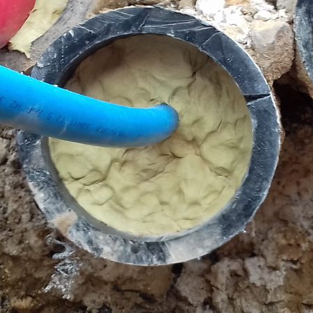 A blue cable inside a filled pipe