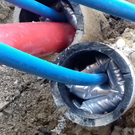 A blue cable going into a concrete pipe